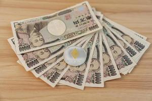 japanische yen-banknote mit silbernem ethereum oder eth-kryptowährung auf dem tisch. Steuern, Rezessionswirtschaft, Inflation, Krypto, Investitionen und dezentrale Finanzkonzepte foto
