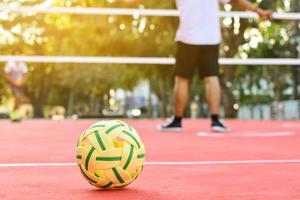 sepak takraw ball auf rotem boden des außenplatzes, unscharfer hintergrund, freizeitaktivitäten und outdoor-sportarten in südostasiatischen ländern konzept. foto