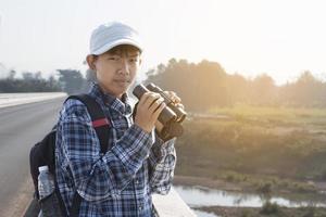 Der asiatische Junge benutzt ein Fernglas, um während des Sommercamps die Vögel im tropischen Wald zu beobachten, eine Idee, um Kreaturen und Wildtiere und Insekten außerhalb des Klassenzimmers zu lernen. foto