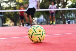 sepak takraw ball auf rotem boden des außenplatzes, unscharfer hintergrund, freizeitaktivitäten und outdoor-sportarten in südostasiatischen ländern konzept. foto