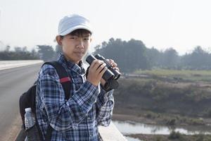 Der asiatische Junge benutzt ein Fernglas, um während des Sommercamps die Vögel im tropischen Wald zu beobachten, eine Idee, um Kreaturen und Wildtiere und Insekten außerhalb des Klassenzimmers zu lernen. foto
