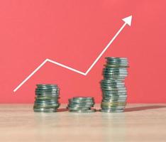 Ein Stapel Metallmünzen und ein Diagramm auf rotem Hintergrund. Einkommenswachstum im Geschäft, hohe Rentabilität foto