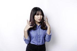 ein porträt einer asiatischen frau, die ein blaues hemd trägt, das durch weißen hintergrund isoliert ist, sieht deprimiert aus foto