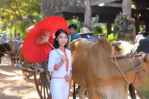 asiatische frau, die typisches thailändisches kleid mit rotem regenschirm trägt., thailändisches kostüm foto