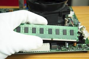 Seitenansichtmechaniker, der RAM des Computer-Motherboards hält foto