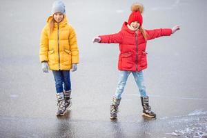 Entzückende kleine Mädchen, die auf der Eisbahn Schlittschuh laufen foto