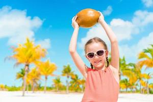 kleines entzückendes Mädchen mit großer Kokosnuss am Strand foto