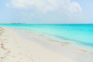 idyllischer tropischer strand in der karibik mit weißem sand, türkisfarbenem ozeanwasser und blauem himmel foto