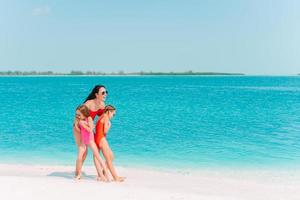 Entzückende kleine Mädchen und junge Mutter am tropischen weißen Strand foto