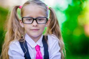 Porträt eines glücklichen kleinen Schulmädchens mit Brille im Freien foto