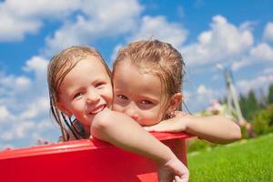 zwei entzückende kleine glückliche mädchen, die spaß im freien am sommertag hintergrund blauer himmel haben foto