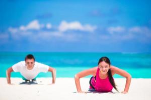 Junges Fitness-Paar macht Liegestütze beim Outdoor-Cross-Training am tropischen Strand foto