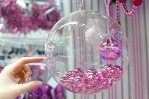 frau, die weihnachtsglasschale mit kleinen rosa kugeln im geschäft hält foto