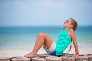 kleines entzückendes mädchen, das musik über kopfhörer am strand hört foto