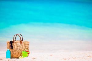 Strandzubehör - Strohsack, Sonnencremeflasche und rote Sonnenbrille am Strand foto