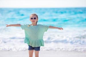 glückliches kleines Mädchen, das während des Karibikurlaubs am Strand spazieren geht foto