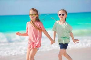 Entzückende kleine Mädchen haben gemeinsam Spaß am weißen tropischen Strand foto