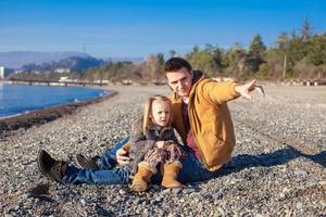 kleines Mädchen und junger Vater am Strand an einem sonnigen Wintertag foto