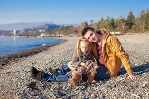 kleines Mädchen und junger Vater am Strand an einem sonnigen Wintertag foto