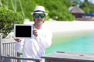 junger Mann am Strand mit Tablet-Computer. Bildschirm anzeigen digitaler PC foto