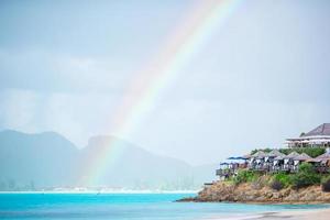 tropischer strand mit türkisfarbenem wasser im ozean, weißem sand und buntem regenbogen foto