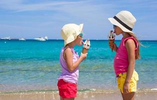 Kleine glückliche Mädchen essen Eis am tropischen Strand foto