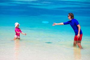 vater und tochter spielen mit fliegender scheibe am strand foto