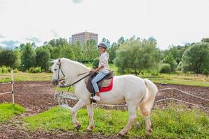 Mädchen, das auf einem weißen Pferd in der Natur reitet foto