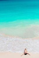 junge frau genießt die sonne beim sonnenbaden am perfekten türkisfarbenen ozean foto