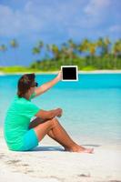 junger Mann, der mit Laptop am tropischen Strand arbeitet foto