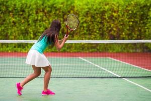 junge aktive frau, die im tropischen urlaub tennis spielt foto