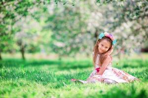Entzückendes kleines Mädchen im blühenden Kirschbaumgarten am Frühlingstag foto