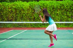 junge aktive frau, die im tropischen urlaub tennis spielt foto