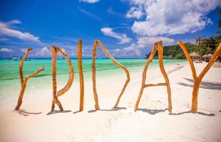 perfekter weißer sandstrand und türkisfarbenes meer auf tropischer insel mit holzbuchstaben aus freitagwort foto