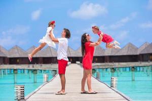 glückliche vierköpfige Familie auf Holzsteg während der Sommerferien im Luxusresort foto