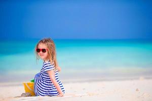 entzückendes kleines mädchen, das während des tropischen urlaubs mit strandspielzeug spielt foto