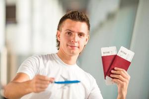 junger mann mit kleinem flugzeug im flughafen, der auf seinen flug wartet foto