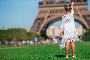 entzückendes kleines mädchen mit karte von paris hintergrund der eiffelturm foto