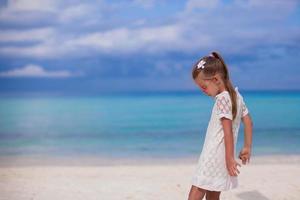 süßes kleines Mädchen, das im tropischen Strandurlaub spazieren geht foto