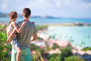 junger vater und kind mit blick auf den tropischen weißen strand auf einer exotischen insel in der karibik foto