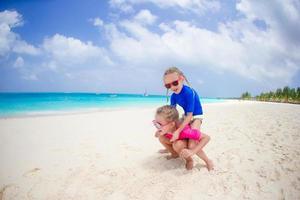 Kleine Mädchen haben Spaß am tropischen Strand und spielen zusammen am Strand foto