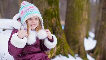 entzückendes kleines glückliches mädchen hat spaß am verschneiten wintertag im freien foto