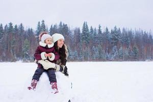 kleines Mädchen und glückliche Mutter genießen den verschneiten Wintertag foto