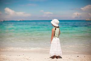 entzückendes kleines Mädchen, das auf tropischem weißem Strand geht foto