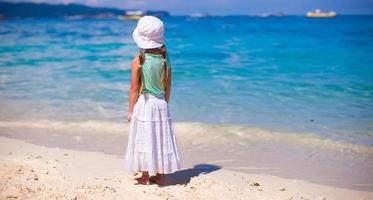 entzückendes kleines Mädchen, das auf tropischem weißem Strand geht foto