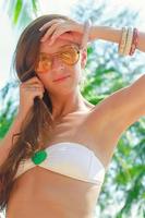 Nahaufnahme einer attraktiven jungen Frau mit Sonnenbrille am Strand foto