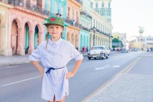 Entzückendes kleines Mädchen in der beliebten Gegend in Alt-Havanna, Kuba. Porträt des Kindes Hintergrund Klassisches amerikanisches Oldtimer foto