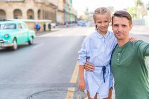 familie von vater und kleinem mädchen, die selfie in der beliebten gegend in alt-havanna, kuba machen. kleines Kind und junger Vater im Freien auf einer Straße von Havanna foto