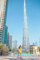 glückliches mädchen, das in dubai mit wolkenkratzern im hintergrund geht. foto