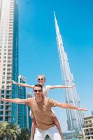 glückliche familie, die in dubai mit wolkenkratzern im hintergrund geht. foto